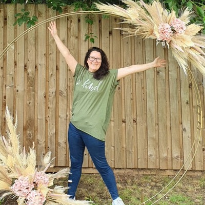 Sarah, owner of Sarah's Flowers Cheshire, standing beneath a decorative dried flower arch.